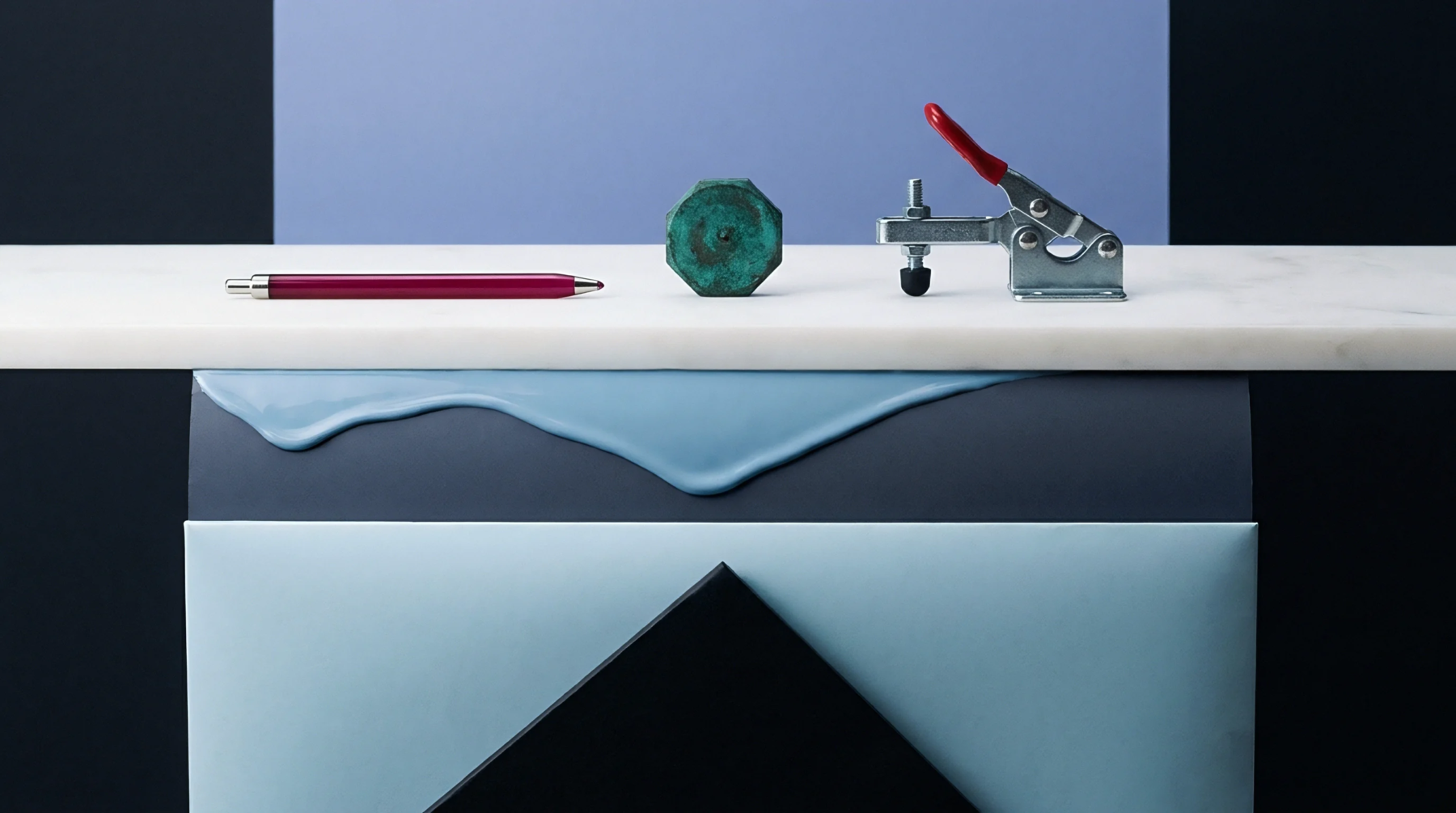 A marble surface holds a metal toggle clamp, a machined green part, and a red marker inside a studio manufacturing display.